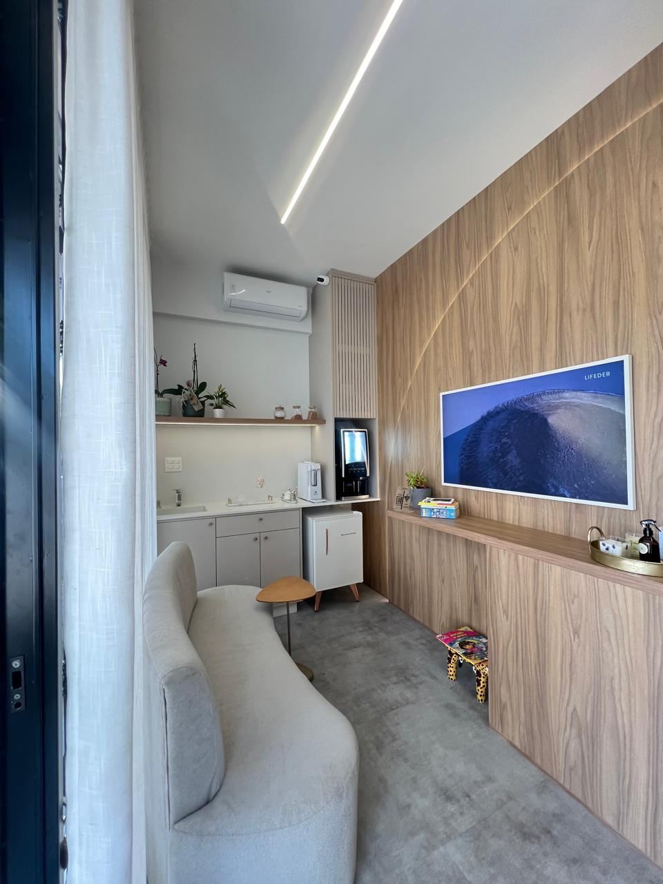 Ambiente reformado com painel de madeira, iluminação linear e TV embutida